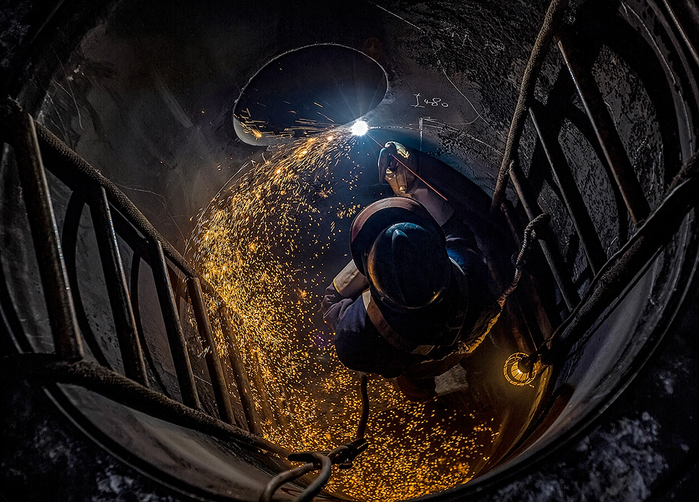 《“井”上添花》作品說明：這是水富云天化維保事業部的一名焊工師傅在罐子內部作業的場景，焊花飛舞，照亮了整個設備